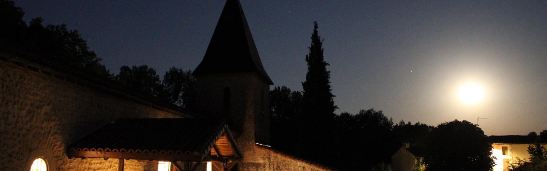 L'église de Quinçay vue de nuit en pose longue, la lune ressemble au soleil et on voit de la lumière sortir de l'Eglise