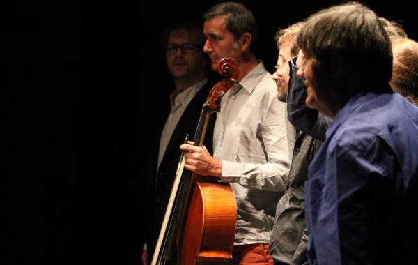 une photo en clair obscur de musiciens saluant le public