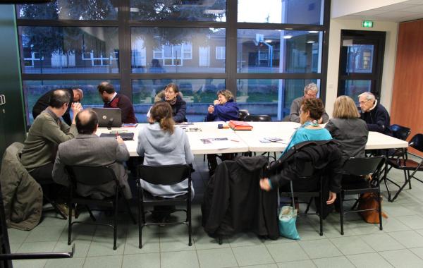 Une assemblée générale de l'association. Des personnes autour d'une table discutent des projets.