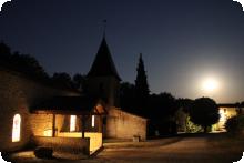 L'église de Quinçay vue de nuit en pose longue, la lune ressemble au soleil et on voit de la lumière sortir de l'Eglise