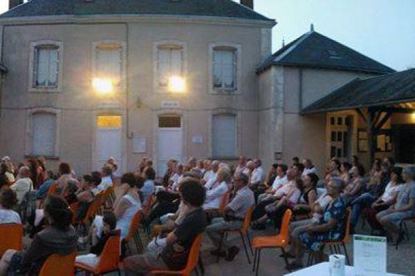 Une photo en fin de journée de la cour de la Mairie de Frozes. Un public très nombreux écoute les musiciens.
